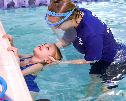 Toddler holds the wall during swim lesson